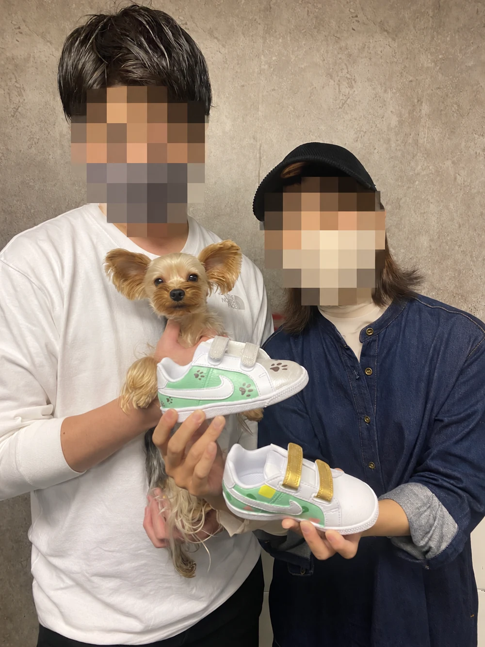 完成したスニーカーと犬を抱えるお客様2名。お客様の顔はモザイク処理済み。